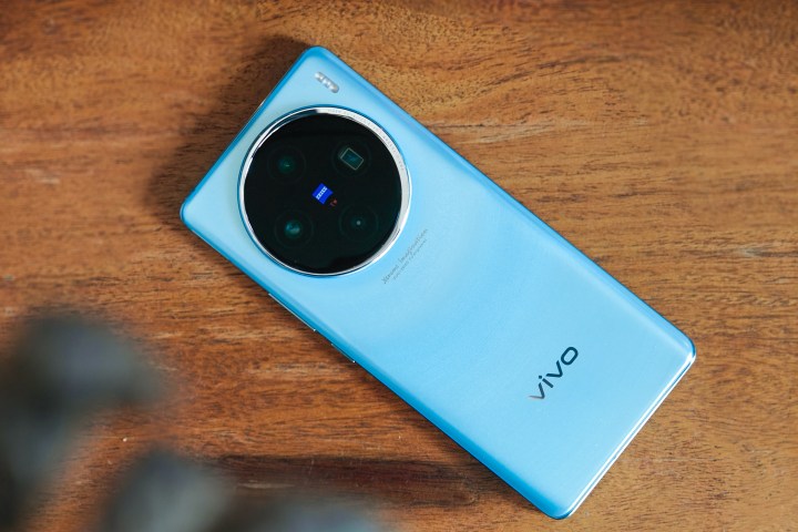 Vivo X100 Glacier Blue on a wooden table.