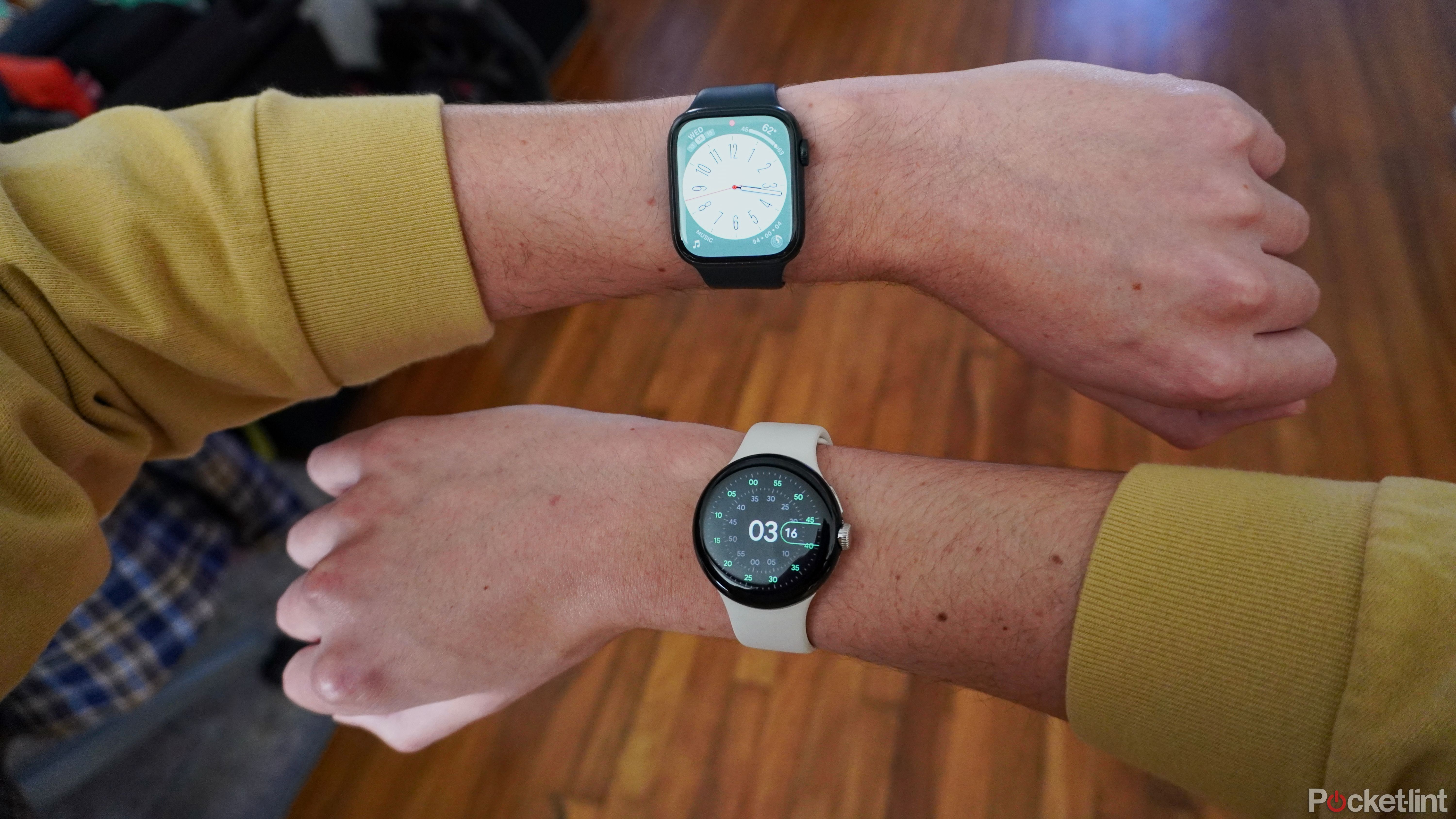 One wrist wearing an Apple Watch over another wrist wearing a Pixel Watch.